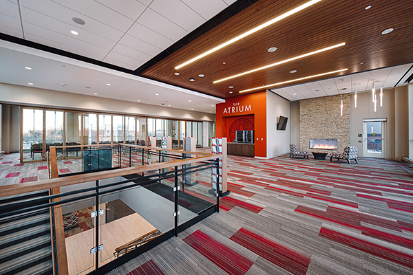 View of the Atrium with a patterned carpet, glass railings, a fireplace, and large windows.