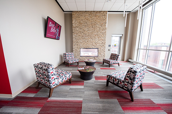 A cozy sitting area with a minimalist stone fireplace, emitting a warm glow.