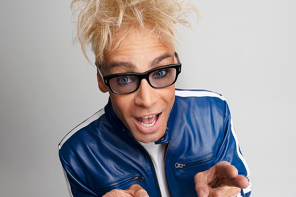 man with blonde hair and black glasses on light background
